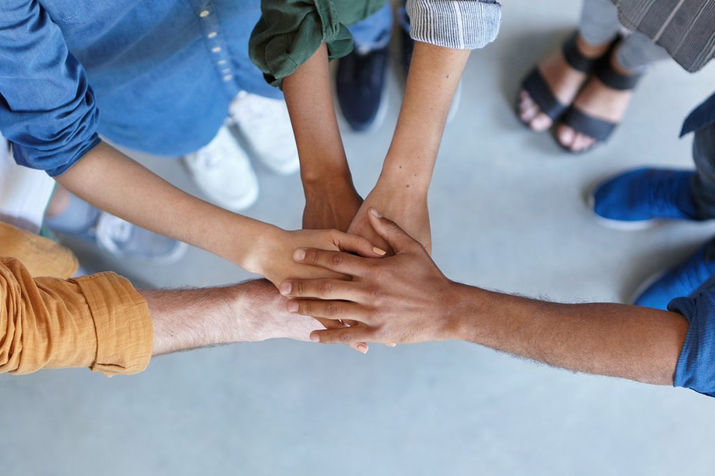 Plusieurs personnes avec des habits différents qui se tiennent la main un au-dessus de l'autre